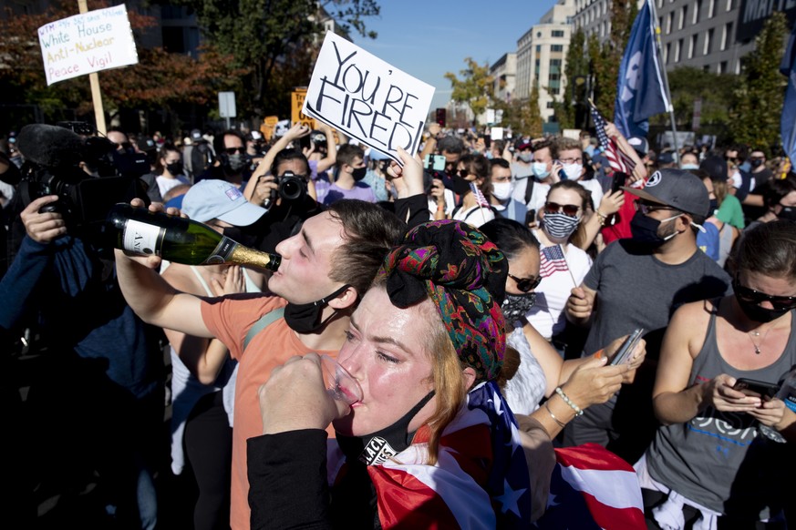 epa08805316 People drink champagne as people celebrate after news organizations called the US 2020 presidential election for Joe Biden, defeating incumbent US President Donald J. Trump, on Black Lives ...