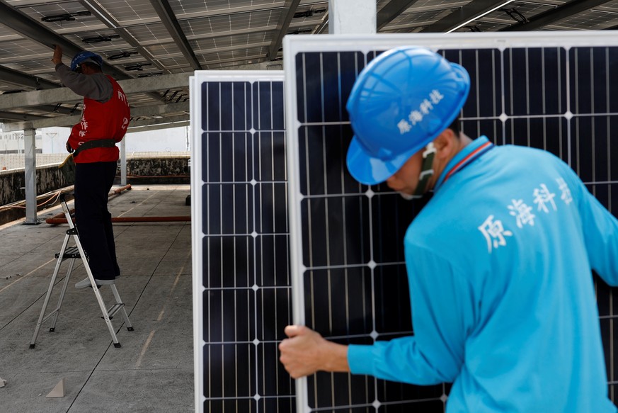 A prisoner (L) places solar panels on the roof of Pingtung Prison in Pingtung, Taiwan February 15, 2017. Picture taken February 15, 2017.REUTERS/Tyrone Siu