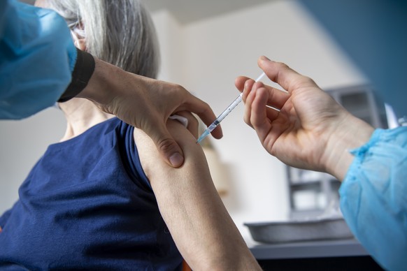 Un membre d&#039;une equipe mobile de vaccination de la protection civile vaudoise, PC, vaccine une femme a l&#039;aide du vaccin Pfizer-BioNTech dans les logements proteges Les Saules, lors du dernie ...