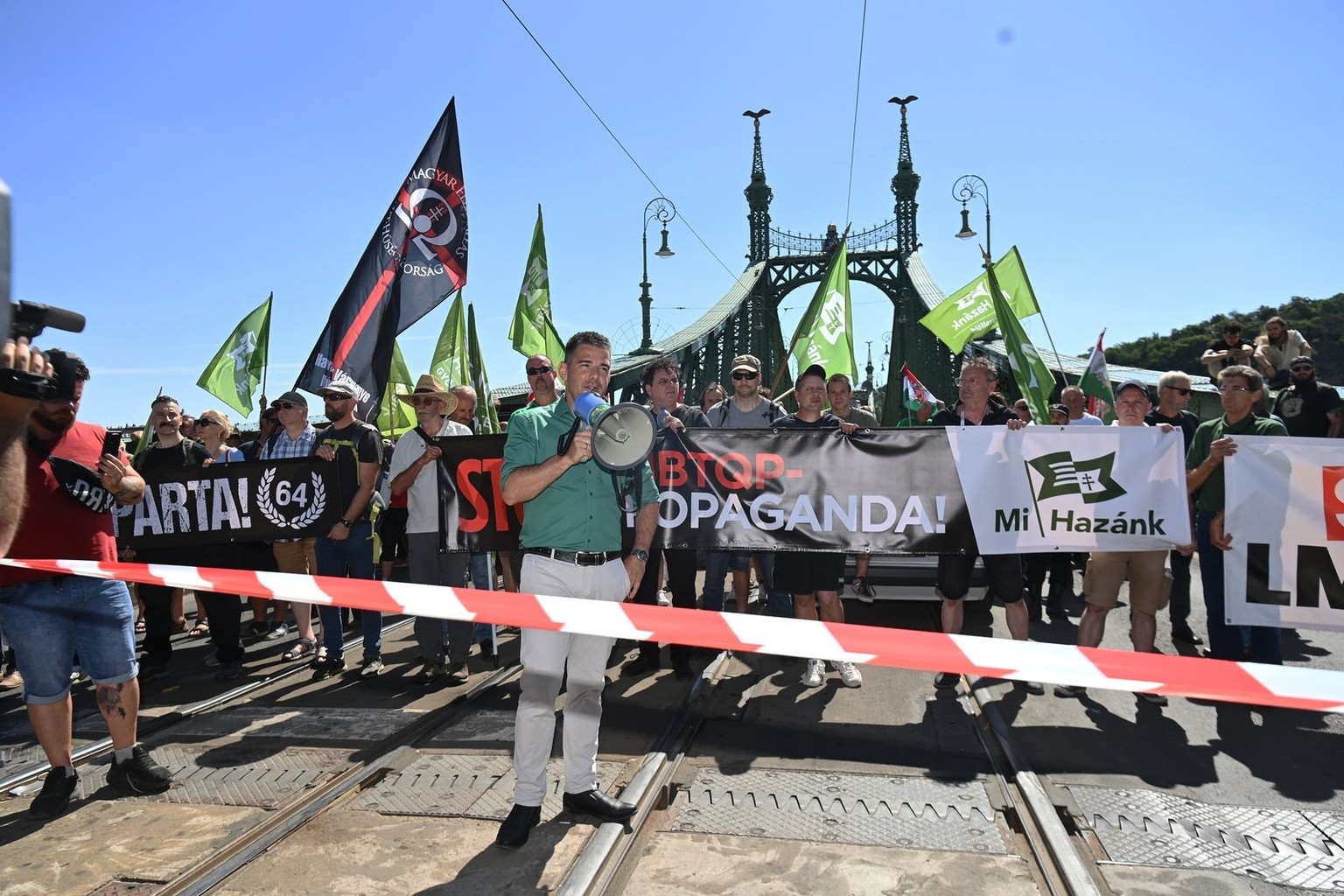 epa12203013 MP and vice chairman of Hungarian far-right political party Our Homeland Movement (Mi Hazank Mozgalom) Elod Novak (C) speaks as they block the Szabadsag (Freedom) bridge during the Budapes ...