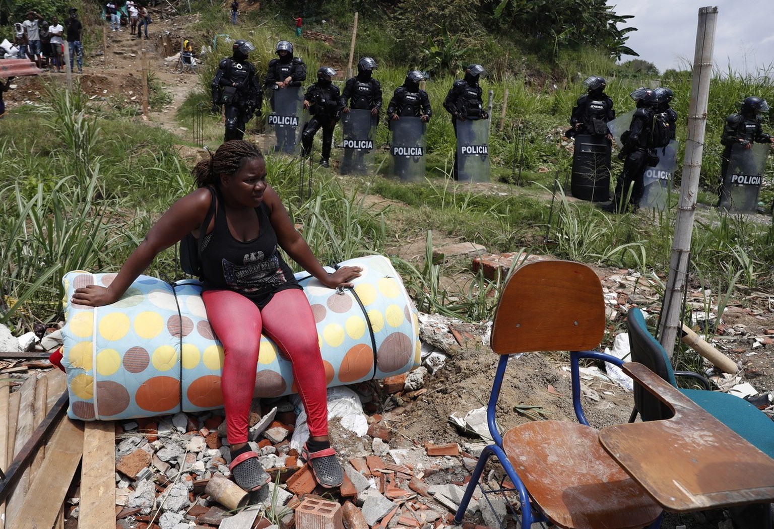 epa10228047 A woman sits on her belongings during the eviction of a property squatted by 1,500 families, at the Navarro zone in Cali, Colombia, 06 October 2022. The eviction of 1,500 families in easte ...