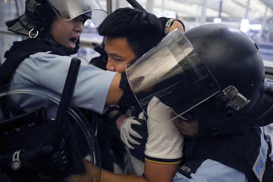 Policemen in riot gears arrest a protester during a demonstration at the Airport in Hong Kong, Tuesday, Aug. 13, 2019. Chaos has broken out at Hong Kong&#039;s airport as riot police moved into the te ...