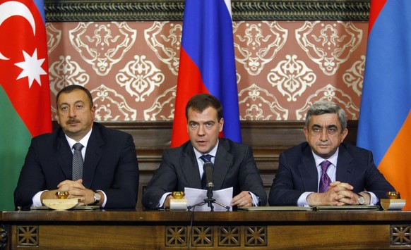 Russian President Dmitry Medvedev, center, reads a text of the declaration signed with Armenian President Serge Sarkisian, right, and Azerbaijani President Ilham Aliev, left, at the Meiendorf Castle o ...