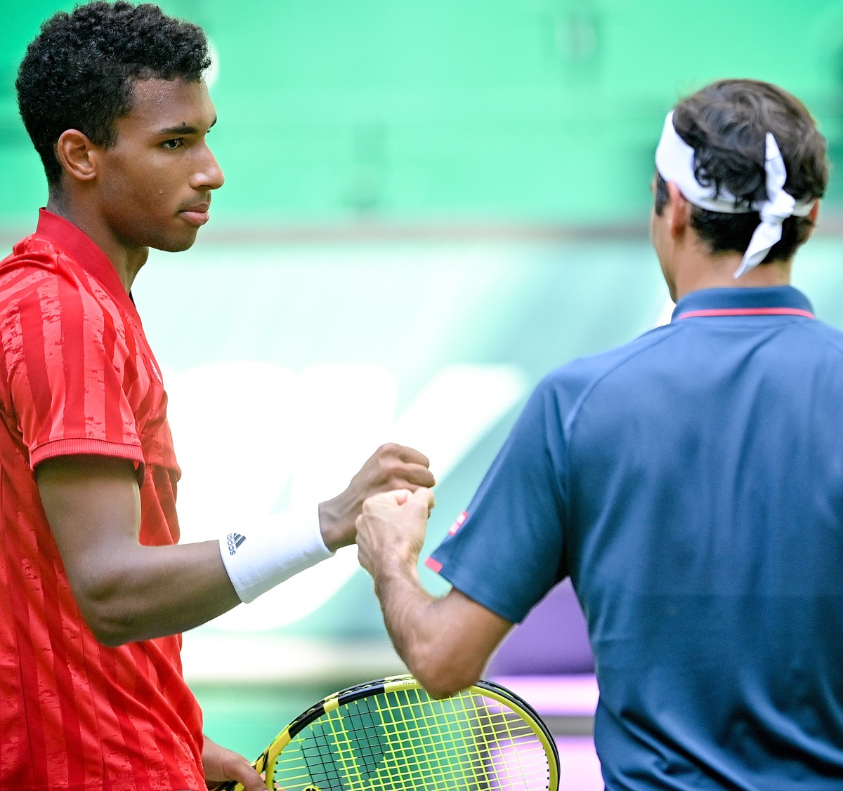 epa09276702 Felix Auger-Aliassime of Canada (L) and Roger Federer of Switzerland (R) fist bump after their round of 16 match against at the ATP Tennis Tournament Noventi Open in Halle (Westphalia), Ge ...