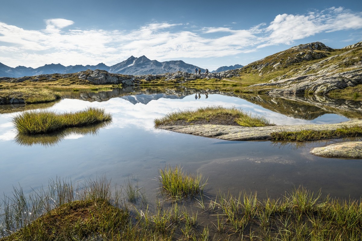 Un groupe randonne au bord d’un lac de montagne dans la région du Grimsel.