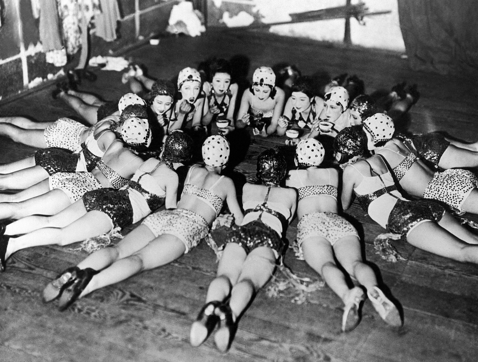 These Japanese chorus girls from a revue running at a Tokyo theater take a break for a moment behind stage to refresh themselves with iced drinks, Aug. 27, 1932. (AP Photo)