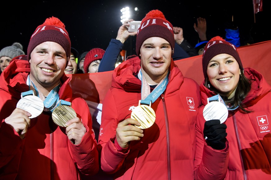 Silver and Bronze medals, Beat Feuz of Switzerland, left, Gold medal, Dario Cologna of Switzerland, center, and Silver medal, Wendy Holdener of Switzerland, right, celebrate at the House of Switzerlan ...