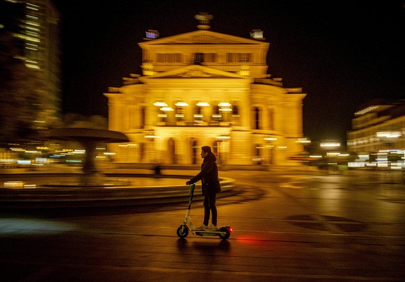 A man drives an E-scooter over the square in front of the Old Opera in Frankfurt, Germany, Saturday, Nov. 7, 2020. (AP Photo/Michael Probst)