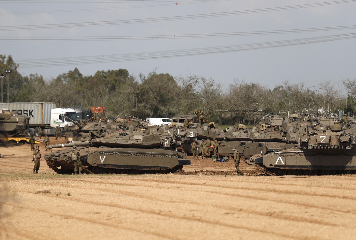 epa07464677 Israeli soldiers stand near their Merkava tanks and APCs, at a gathering point next to the border with Gaza, 26 March 2019. Israeli army is targeting Hamas militant installations in the Ga ...