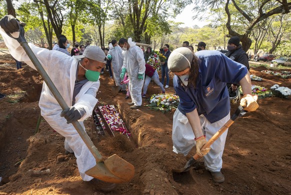 Cemetery workers bury 65-year-old Maria Joana Nascimento, whose family members, behind, suspect died of COVID-19, at Vila Formosa cemetery in Sao Paulo, Brazil, Thursday, Aug. 6, 2020. Brazil is neari ...
