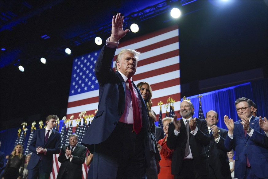 Republican presidential nominee former President Donald Trump waves as he walks with former first lady Melania Trump at an election night watch party at the Palm Beach Convention Center, Wednesday, No ...
