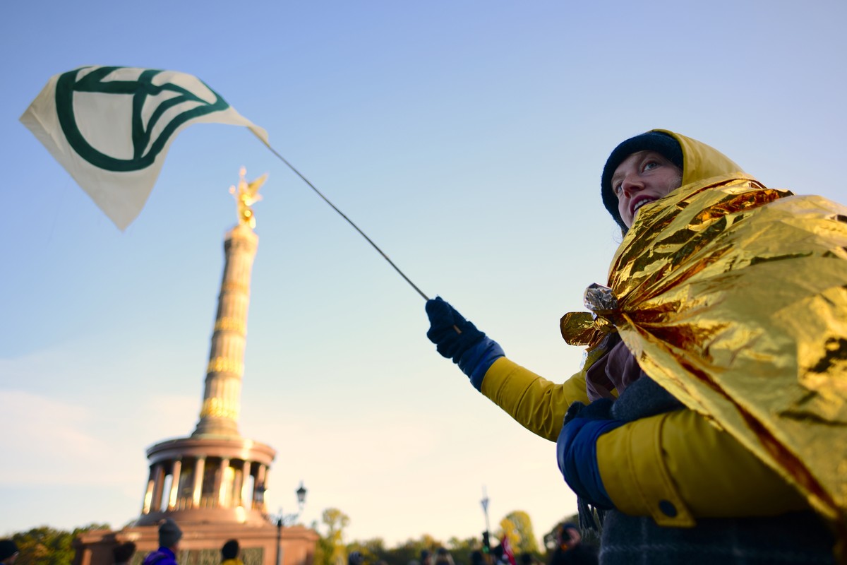 epaselect epa07902850 An activist of global environment movement Extinction Rebellion (XR) waves a flag as they block the traffic junction 'Grosser Stern' around the victory column in Berlin ...
