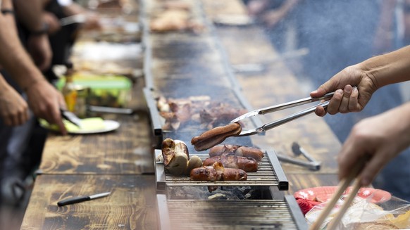 Ein Besucher wendet einen Cervelat auf dem Grill, waehrend der Bundesfeier am Freitag, 1. August 2025 auf dem Bundesplatz in Bern. (KEYSTONE/Peter Klaunzer)