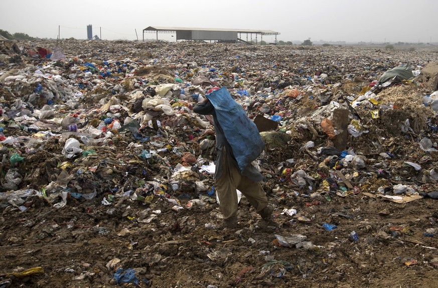 An Afghan refugee scavenges for recyclable material from garbage, mostly plastic shopping bags, to earn a living for his family, in the suburbs of Islamabad, Pakistan, Tuesday, May 6, 2018. World Envi ...