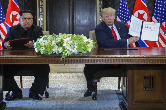 U.S. President Donald Trump holds up the document that he and North Korea leader Kim Jong Un just signed at the Capella resort on Sentosa Island Tuesday, June 12, 2018 in Singapore. The most tangible  ...