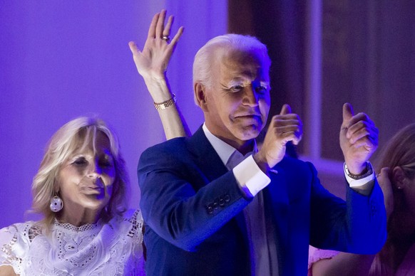 epa09322910 US President Joe Biden (R) and First Lady Jill Biden (L) gesture after watching fireworks on the National Mall from the Truman balcony of the White House, with friends, family and visitors ...