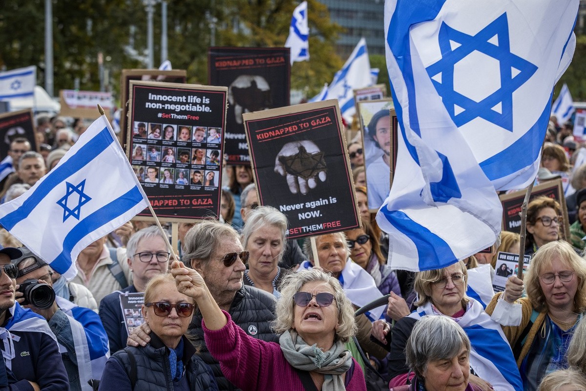 Protesters hold banners with hostages' pictures and Israel national's flags during a gathering next to the European headquarters of the United Nations in Geneva, Switzerland, Sunday, October ...