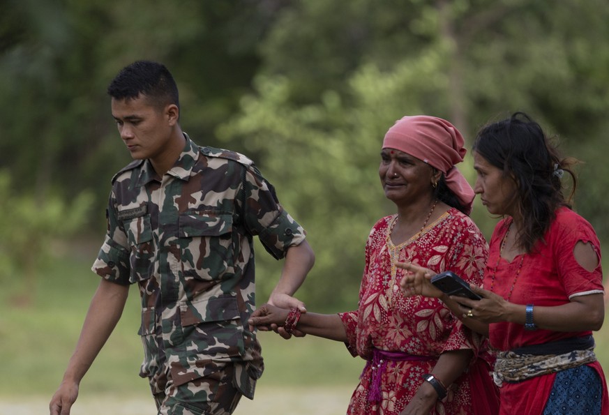 epa13193036 A soldier assists villagers following a flash flood in Trishuli Bazar, Nuwakot district, Nepal, 26 August 2026. Several people were killed, and multiple others were reported missing after  ...