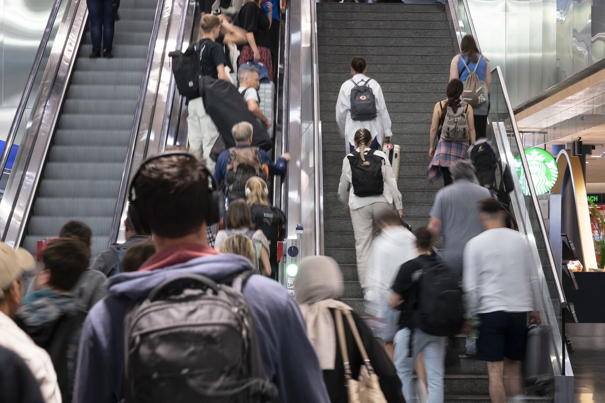 Passagiere nehmen mit Koffern, Taschen und Rucksaecken die Rolltreppe im Flughafen Zuerich, um zum Check-in zu gelangen, aufgenommen am Samstag, 13. Juli 2024 in Kloten. (KEYSTONE/Gaetan Bally)