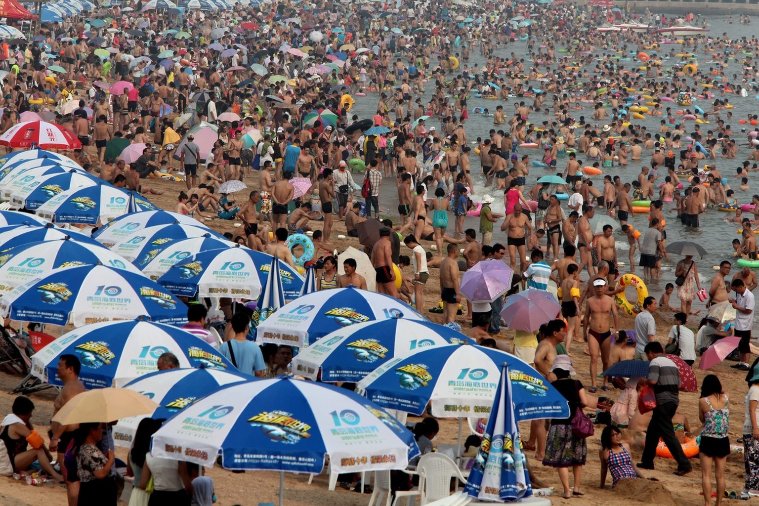 epa03800675 Tens of thousands of locals and tourists pack onto a bathing beach of Huiquan Bay in coastal Qingdao city, eastern China's Shandong province, 25 July 2013 China's tourism industr ...