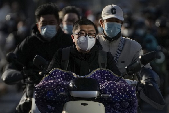 Motorists wearing face masks ride their electric-powered scooters on a street during the opening ceremony of the 20th National Congress of China&#039;s ruling Communist Party in Beijing, Sunday, Oct.  ...