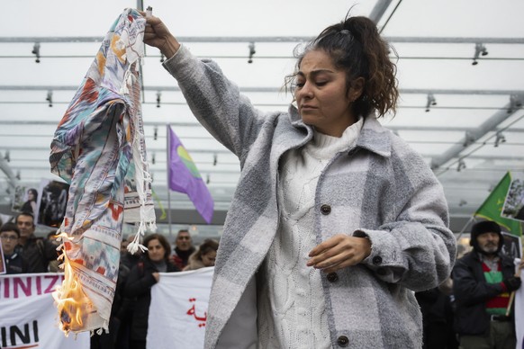 An Iranian woman burns her headscarf during a rally against the death of Iranian Mahsa Amini in Bern, Switzerland, Tuesday, September 27, 2022. They were protesting against the death of Iranian Mahsa  ...