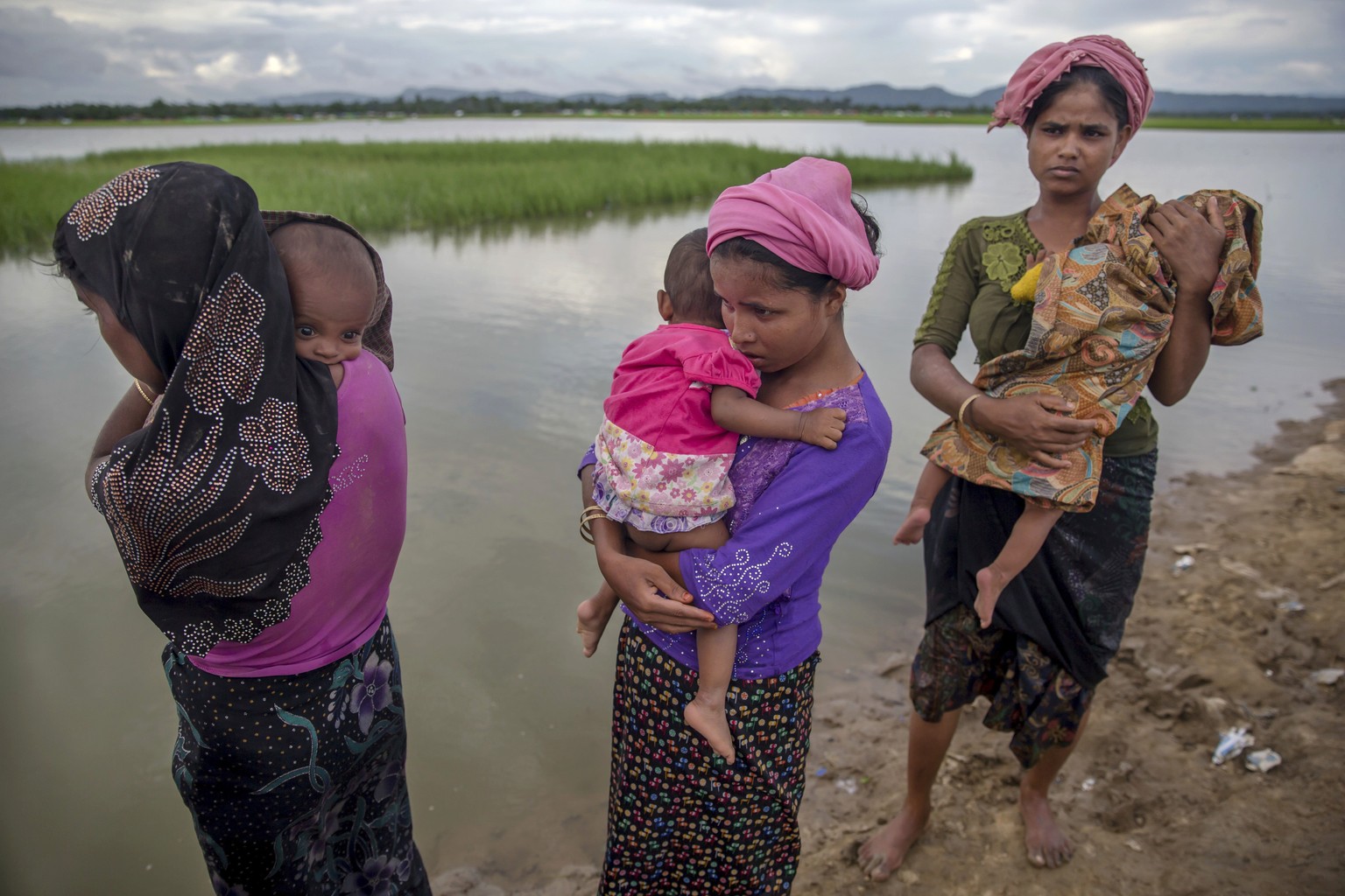 FILE- In this Oct. 18, 2017, file photo, Rohingya Muslim women, who crossed over from Myanmar into Bangladesh, stand holding their sick children after Bangladesh border guard soldiers refused to let t ...