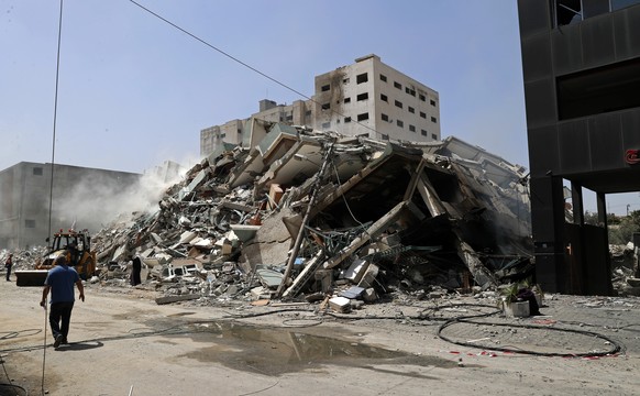 People inspect the rubble of a building that was destroyed by an Israeli airstrike on Saturday that housed The Associated Press, broadcaster Al-Jazeera and other media outlets, in Gaza City, Sunday, May 16, 2021. (AP Photo/Adel Hana)