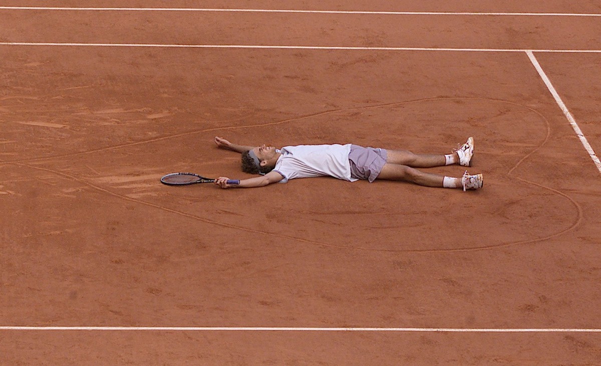 Brazil's Gustavo Kuerten lies in a heart he drawn on the clay after winning the men's final match against Spain's Alex Corretja in the French Tennis Open at Roland Garros stadium Sunday ...