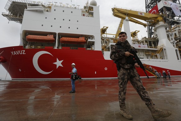 FILE - In this Thursday, June 20, 2019 file photo, a Turkish police officer patrols the dock, backdropped by the drilling ship &#039;Yavuz&#039; to be dispatched to the Mediterranean, at the port of D ...