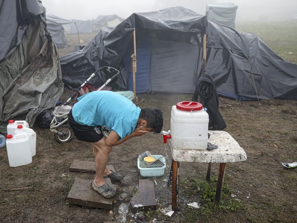 A migrant man washes his face at a makeshift camp housing migrants mostly from Afghanistan, in Velika Kladusa, Bosnia, Tuesday, Oct. 12, 2021. Hundreds of migrants _ including small children, babies a ...