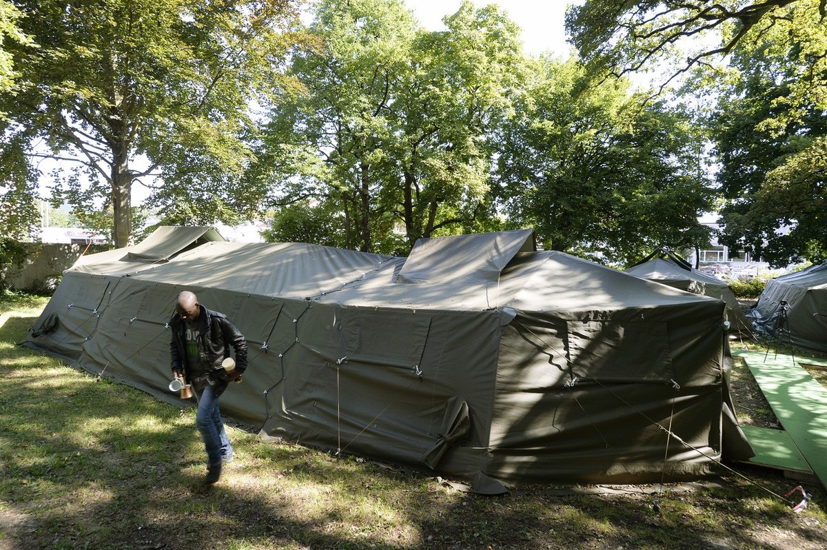 Ein Asylsuchender neben Armeezelten, die als temporaere mobile Asylunterkuenfte dienen, in Aarau, aufgenommen am Medientermin am Freitag, 31. Juli 2015. Die Armeezelte werden in diesen Tagen von den e ...