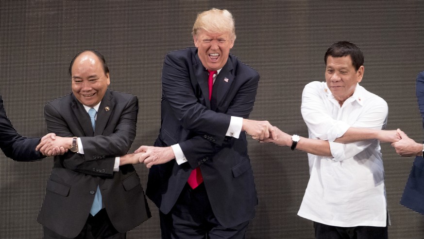 CORRECTS ID TO VIETNAMESE PRIME MINISTER NGUYEN XUAN PHUC - U.S. President Donald Trump, center, reacts as he does the "ASEAN-way handshake" with Vietnamese Prime Minister Nguyen Xuan Phuc, ...