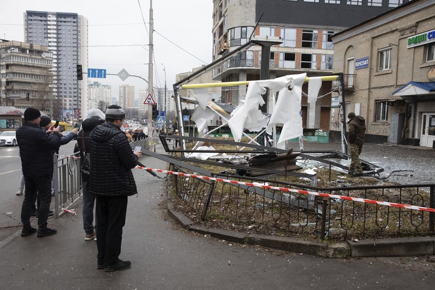 People inspect the consequences of Russian shelling in Kyiv, Ukraine, Thursday, Feb. 24, 2022. Russian troops have launched their anticipated attack on Ukraine. Big explosions were heard before dawn i ...