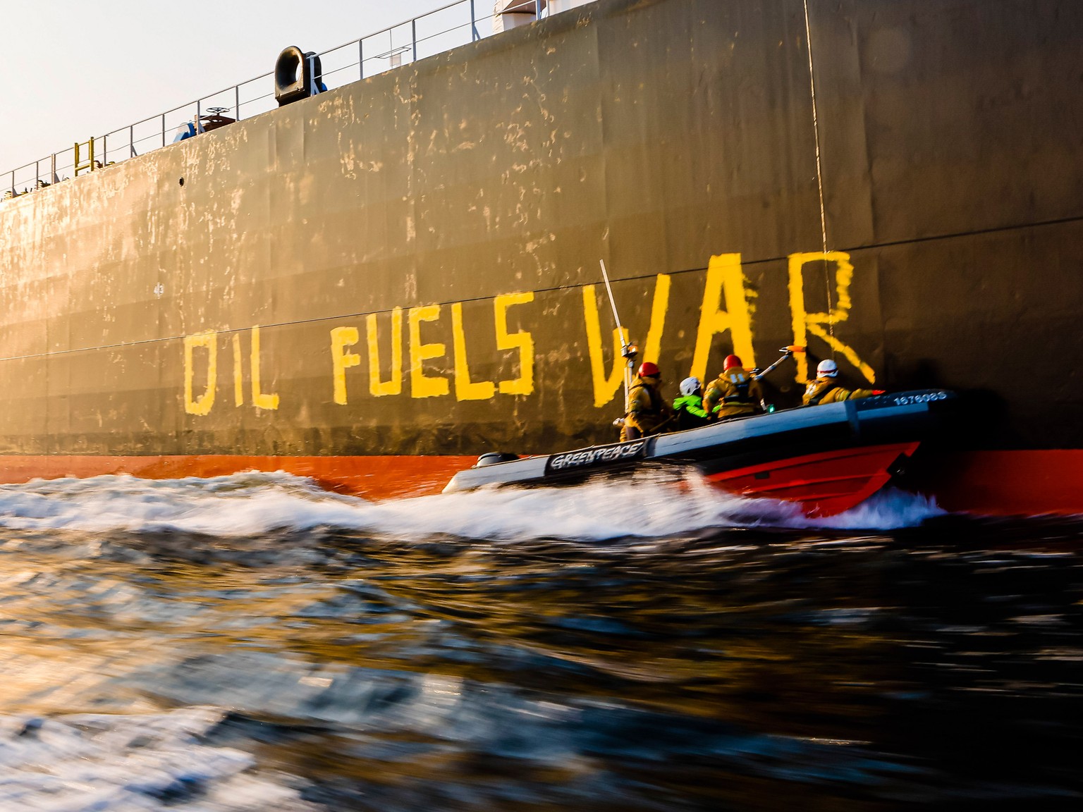 Activists of the environmental organization Greenpeace paint the words &#039;Oil fuels war&#039; on the hull of a ship carrying Russian oil near the German island Fehmarn, Germany, Wednesday, March 23 ...