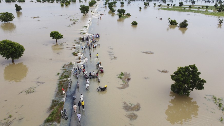 People walk through floodwaters after heavy rainfall in Hadeja, Nigeria, Monday, Sept 19, 2022. Nigeria is battling its worst floods in a decade with more than 300 people killed in 2021 including at l ...