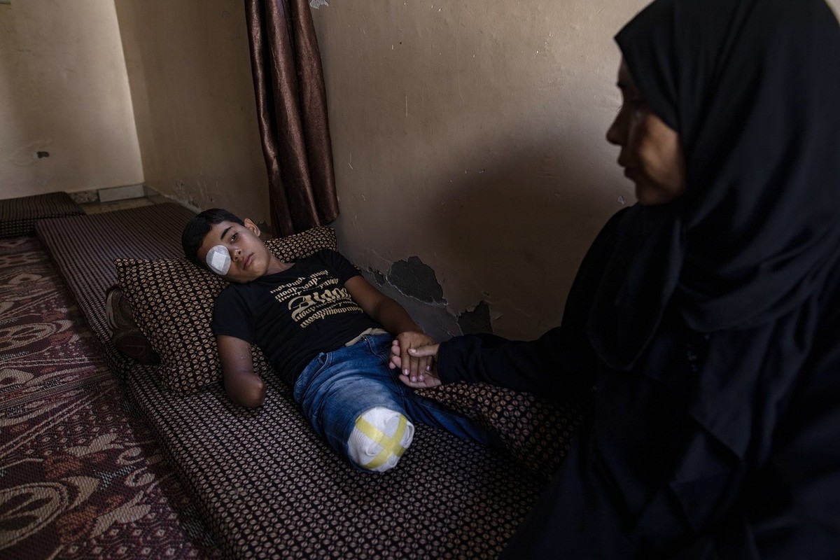 epa11616378 Palestinian teen Wahid Al-Ghalban, 13, rests on a mattress while holding his mother's hand in Khan Yunis, southern Gaza Strip, 19 September 2024 (issued 20 September 2024). Wahid, an  ...