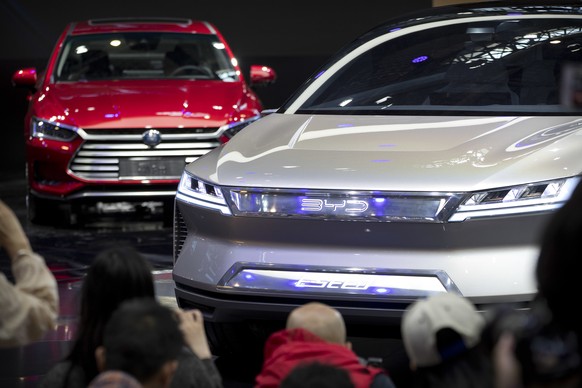FILE - Attendees take photos of the E-SEED electric concept car during a press conference by Chinese automaker BYD at the China Auto Show in Beijing, on April 25, 2018. China&#039;s Commerce Ministry  ...