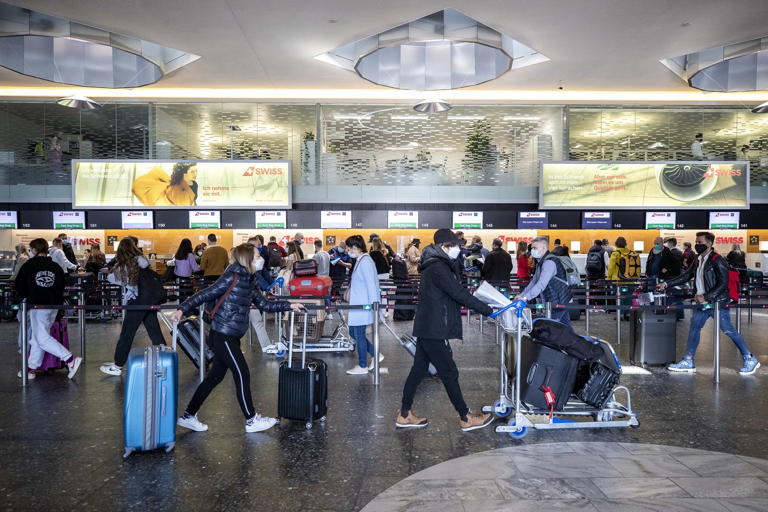 Menschen stehen am Check-In Schalter der Fluggesellschaft Swiss am Flughafen Zuerich, fotografiert am Donnerstag, 1. April 2021. (KEYSTONE/Alexandra Wey)