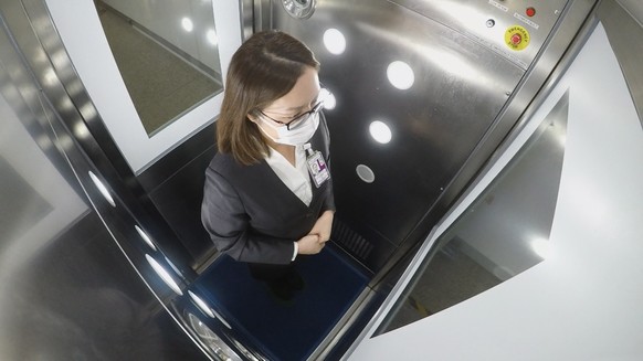 epa08387108 A handout photograph provided by Hong Kong International Airport shows a worker going through CLeanTech, a full-body disinfection channel facility, at Hong Kong International Airport in Ho ...