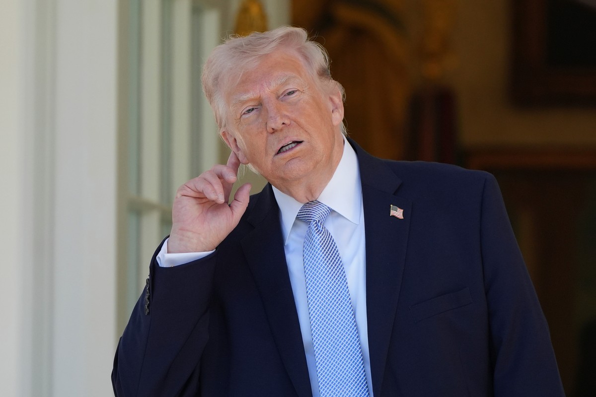 President Donald Trump holds his ear to listen to the music before heading back to the Oval Office after participating in the White House Easter Egg Roll on the South Lawn of the White House, Monday,  ...