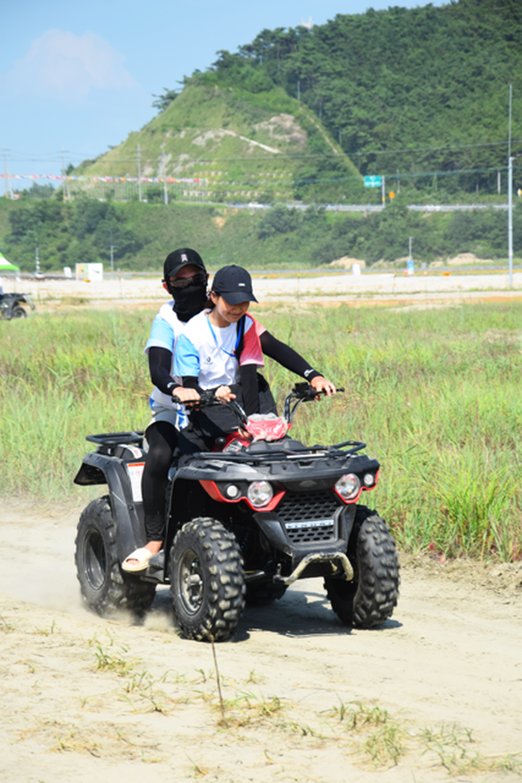 Two people doing quad on the korean jamboree 2023 activities, boy drive at the back, girl is on the front