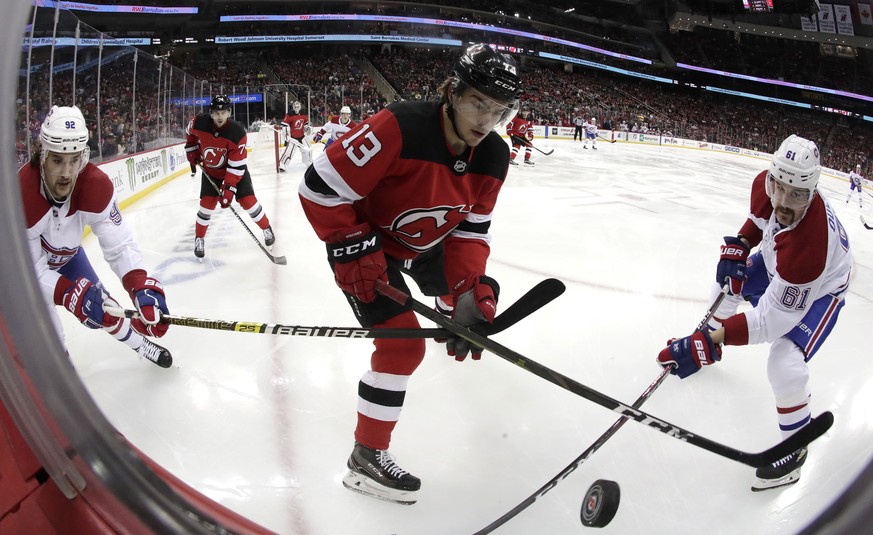 New Jersey Devils center Nico Hischier (13), of Switzerland, competes for the puck with Montreal Canadiens center Jonathan Drouin (92) and defenseman Xavier Ouellet (61), of France, during the first p ...