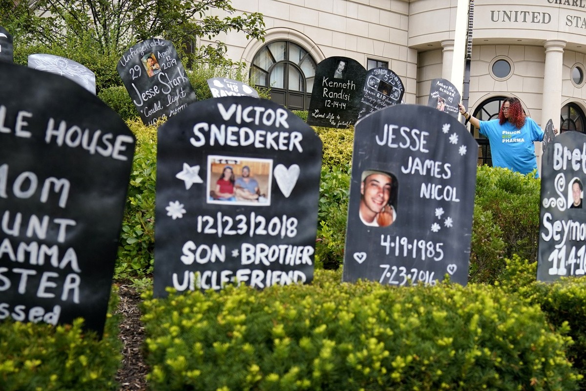 Jayde Newton helps to set up cardboard gravestones with the names of victims of opioid abuse outside the courthouse where the Purdue Pharma bankruptcy is taking place in White Plains, N.Y., Monday, Au ...