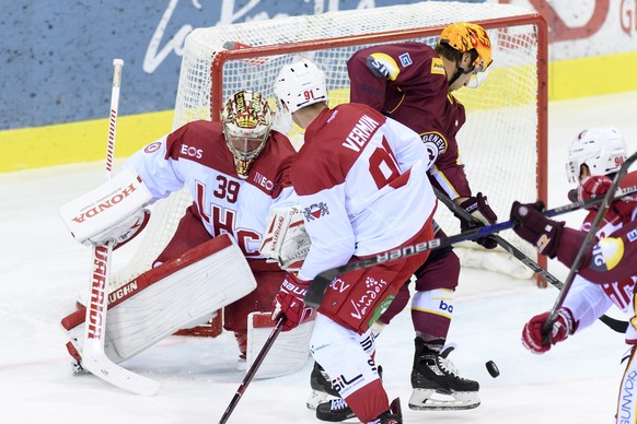 Le joueur lausannois, Joel Vermin, centre, a la lutte pour le puck avec le joueur genevois, Kevin Romy, droite, auteur du 1.0, devant le gardien lausannois, Cristobal Huet, gauche, lors du match du ch ...