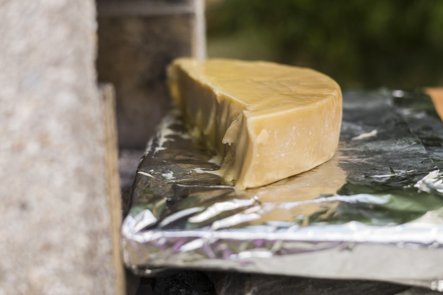 Preperation of Raclette, a Swiss dish based on heating the cheese and scraping off (racler) the melted part, over a wood fire in Flanthey, in the Canton of Valais, Switzerland, on July 30, 2016. (KEYS ...