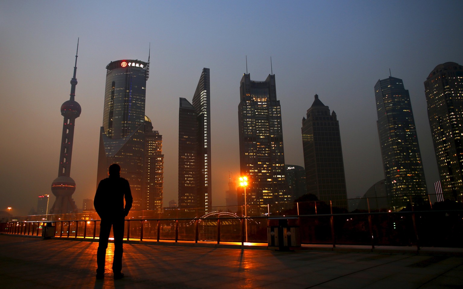 A man looks at the Pudong financial district of Shanghai in this November 20, 2013 file photo. Sentiment at some of Asia's biggest firms deteriorated again in the fourth quarter, falling to a four-yea ...