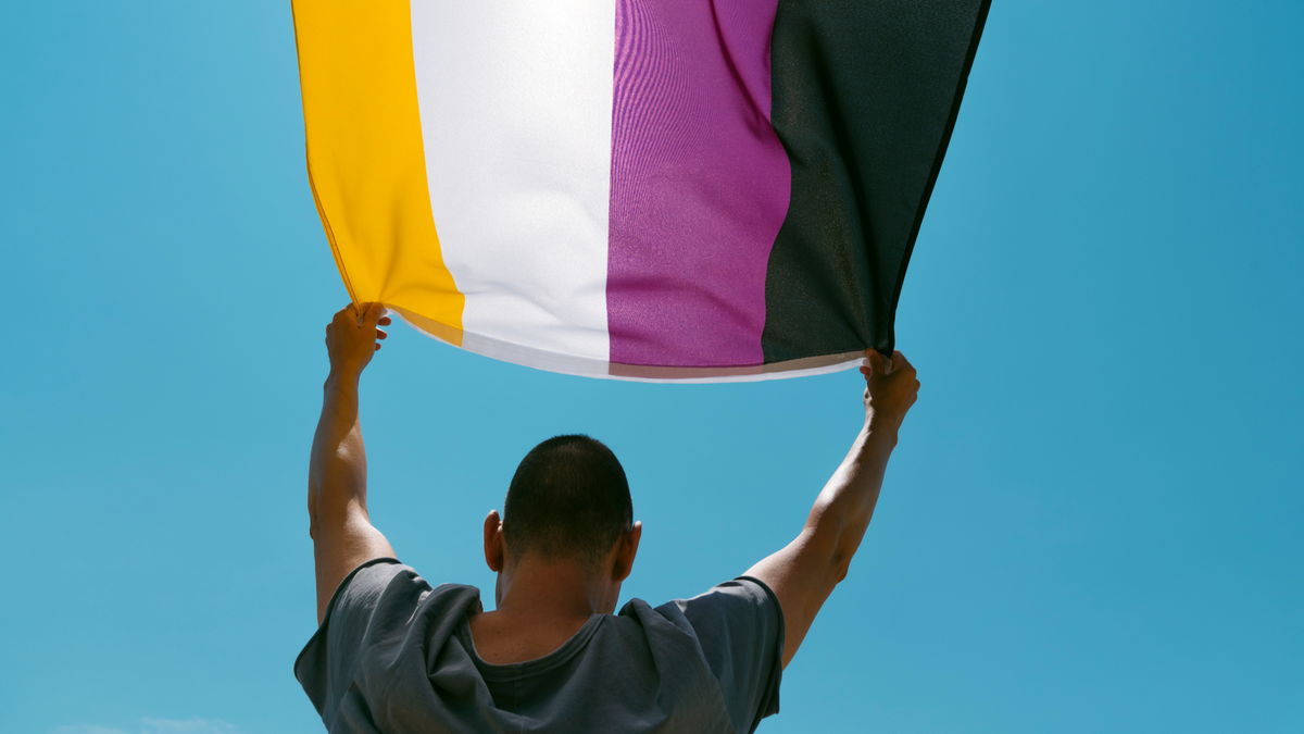 Une personne portant le drapeau des non-binaires