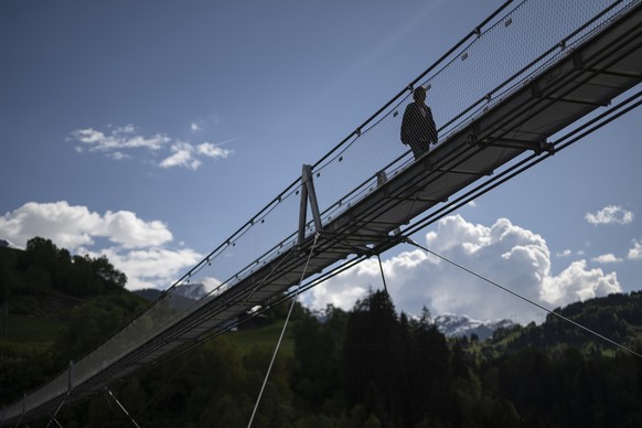 Eine Frau geht ueber La Pendenta, die mit 280 Metern laengste Haengebruecke Graubuendens, am Mittwoch, 14. Mai 2025, in Disentis. (KEYSTONE/Gian Ehrenzeller)