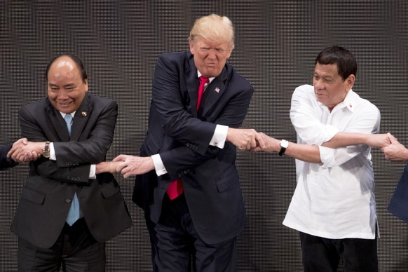 CORRECTS ID TO VIETNAMESE PRIME MINISTER NGUYEN XUAN PHUC - U.S. President Donald Trump, center, reacts as he does the &quot;ASEAN-way handshake&quot; with Vietnamese Prime Minister Nguyen Xuan Phuc,  ...